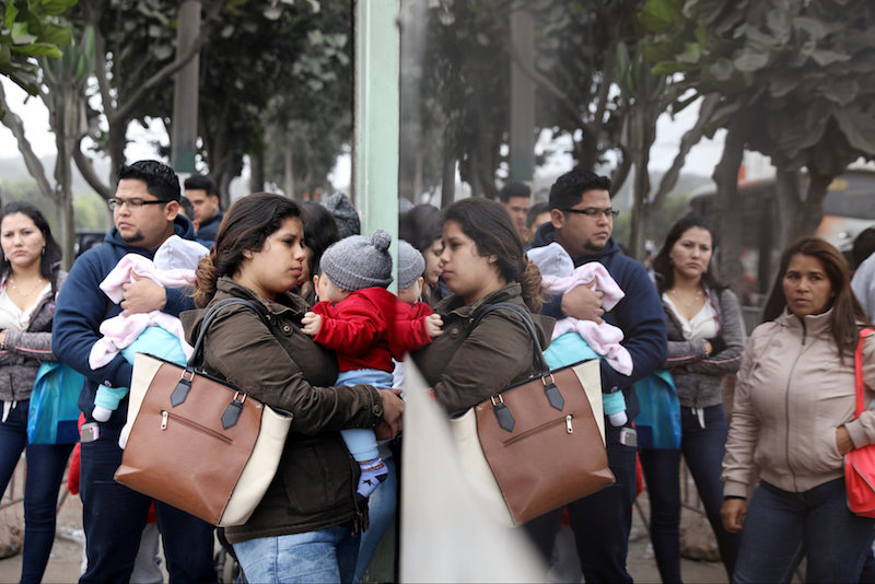 Venezuelan migrants wait at the Interpol headquarters to get paperwork needed for a temporary residency permit in Lima
