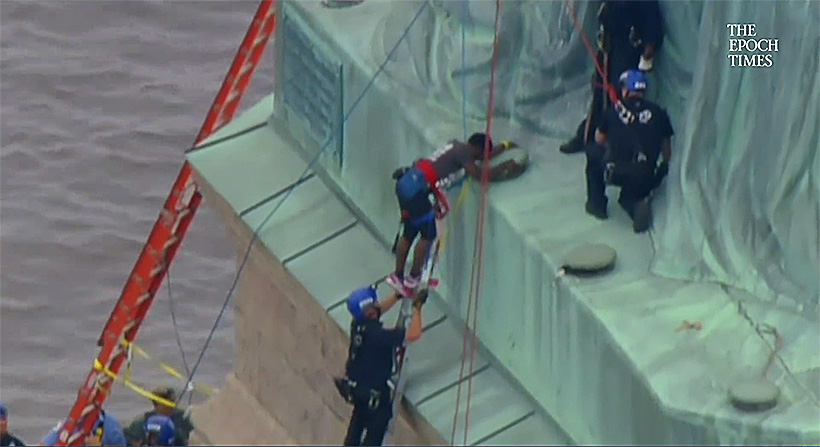 Emergency Service Unit officers assist Okoumou to a ladder whence she could climb down to the ground. (Epoch Times screenshot)