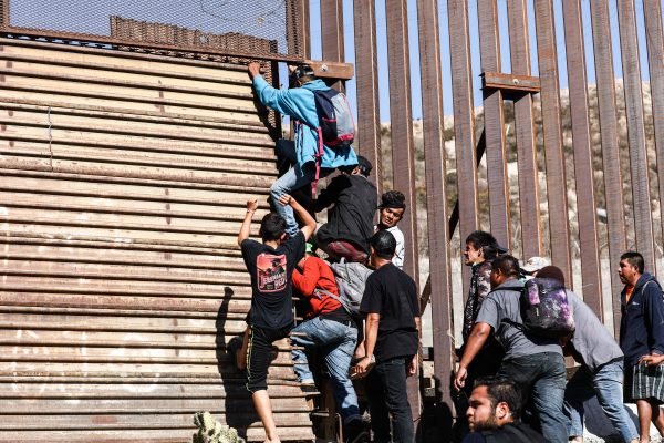 migrant caravan climbs border wall