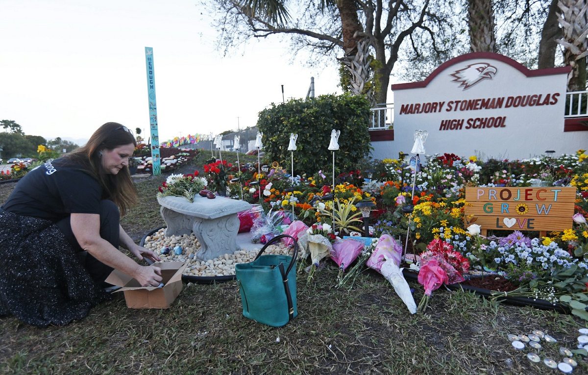 Suzanne Devine Clark, an art teacher at Deerfield Beach Elementary School, places painted stones at a memorial outside Marjory Stoneman Douglas High School