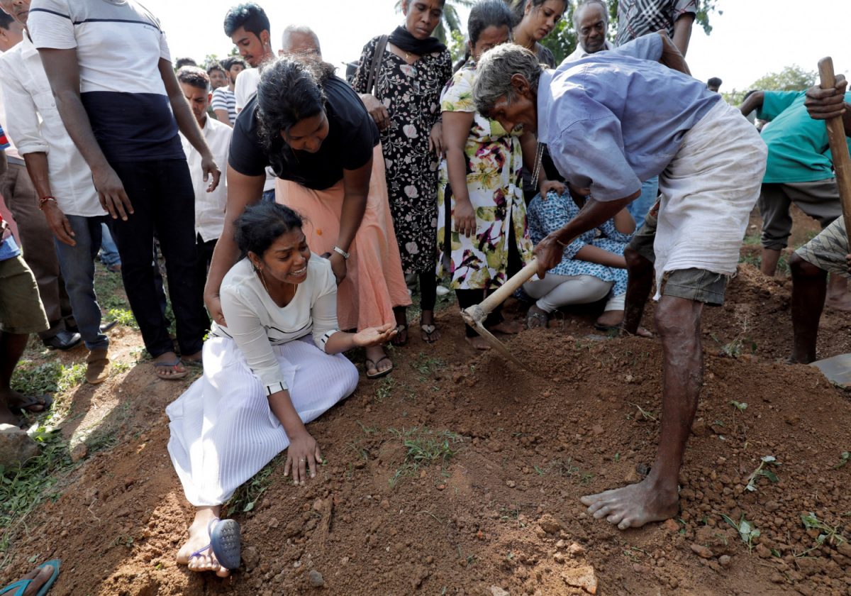 A woman reacts during a mass burial of victims