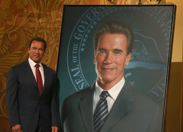 Former California Gov. Arnold Schwarzenegger poses next to his gubernatorial portrait