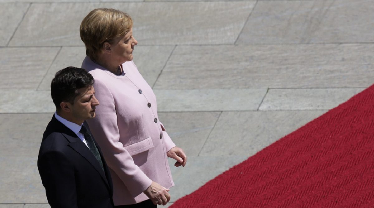German Chancellor Angela Merkel, right, and Ukrainian President Volodymyr Zelenskiy, left, listen to the national anthems during the welcoming ceremony, prior to a meeting