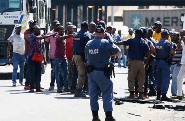 Minibus taxi drivers argue with South African Police Service members during a taxi drivers' riot near the Bloed Taxi Rank