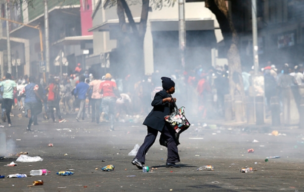 A woman runs for cover during the rioting of taxi drivers near the Bloed Taxi Rank