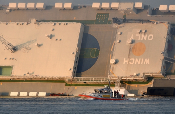 A U.S. Coast Guard boat rides in front of a cargo ship that capsized in the St. Simons Island sound, Ga.