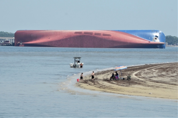 People are shown on Jekyll Island's Driftwood Beach as the Golden Ray cargo ship is capsized