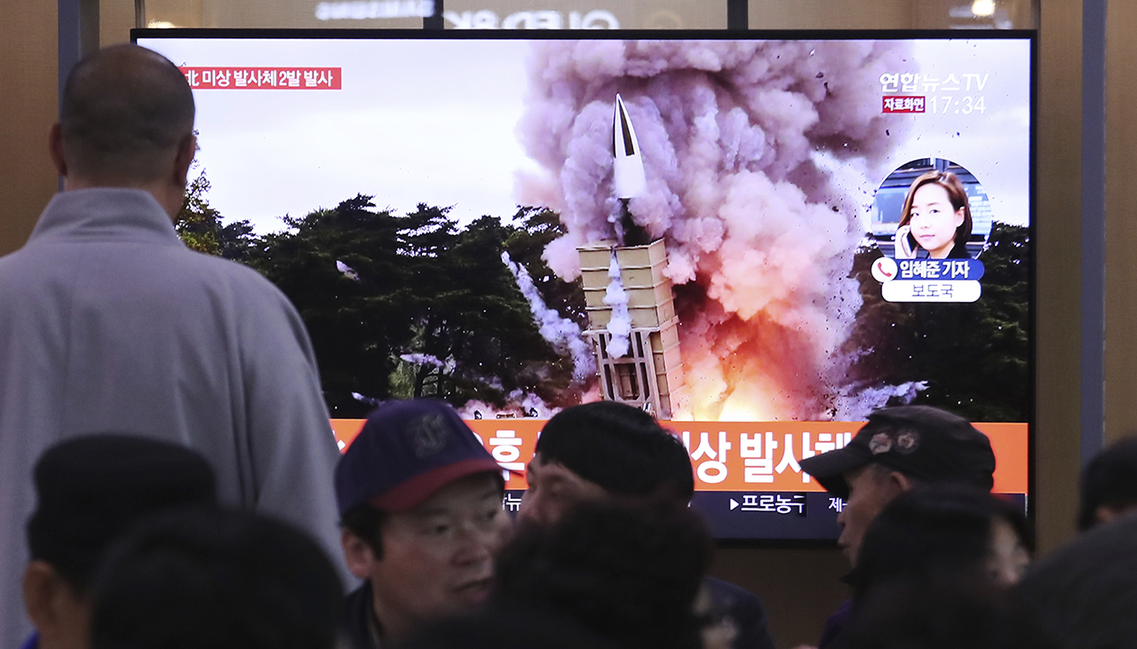 People watch a TV showing a file image of an unspecified North Korean missile launch