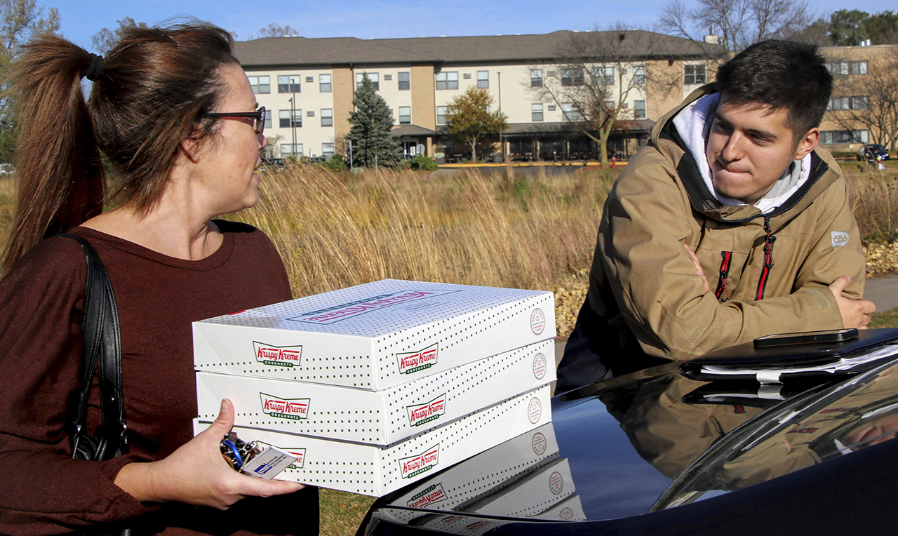 Catherine Newton, left, buys three boxes of Krispy Kreme doughnuts from Jayson Gonzalez