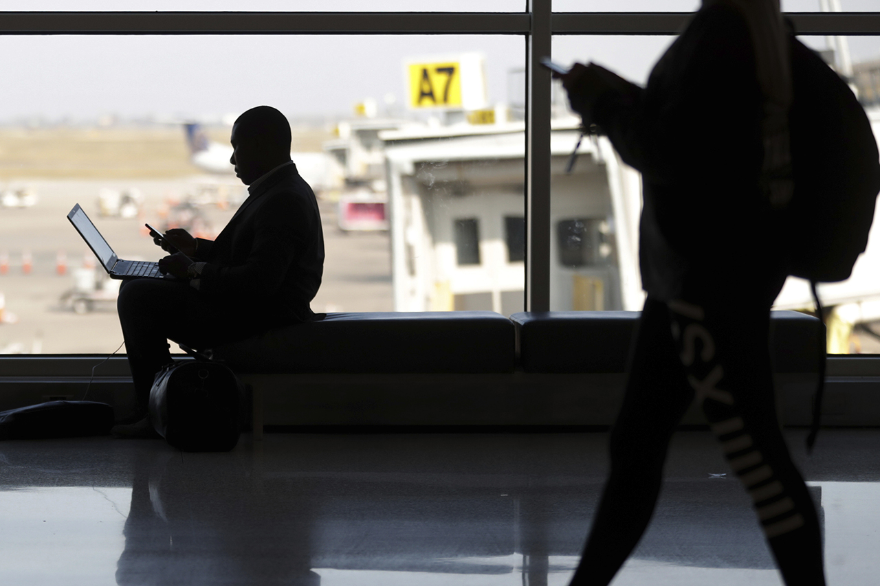 Travelers check their phones at Indianapolis International Airport.