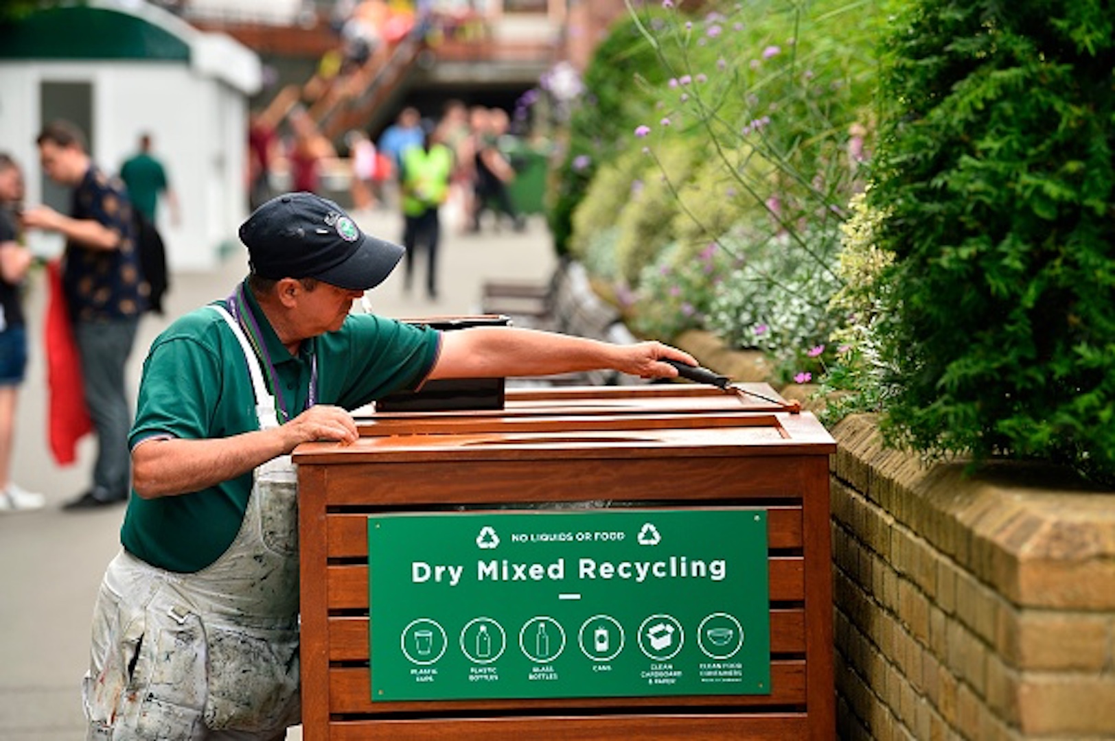 A worker puts touches up the finish on a recycling bin