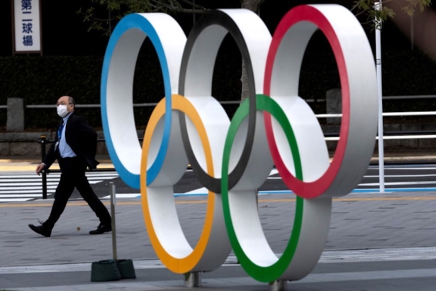 A man wearing a protective face mask, following an outbreak of the coronavirus disease (COVID-19), walks past walk past the Olympic rings in front of the Japan Olympics Museum in Tokyo