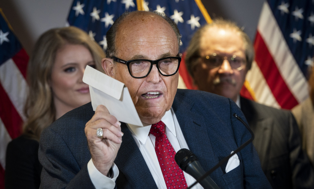Rudy Giuliani holds up a mail-in ballot