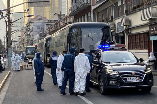 Police and workers stand next to buses
