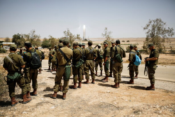 Israeli soldiers gather as they survey the area after a Syrian missile exploded in southern Israel, the Israeli military said, in Ashalim