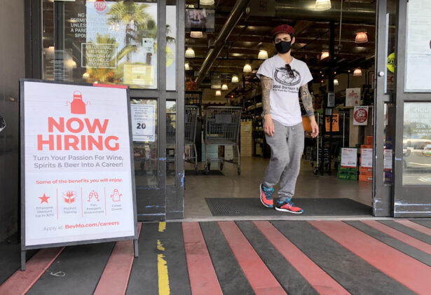 A customer walks by a now hiring sign