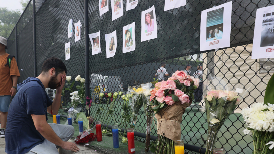 Leo Soto kneels in front of a memorial that includes pictures of missing people in Surfside, Fla., on June 25, 2021. (Joe Raedle/Getty Images)