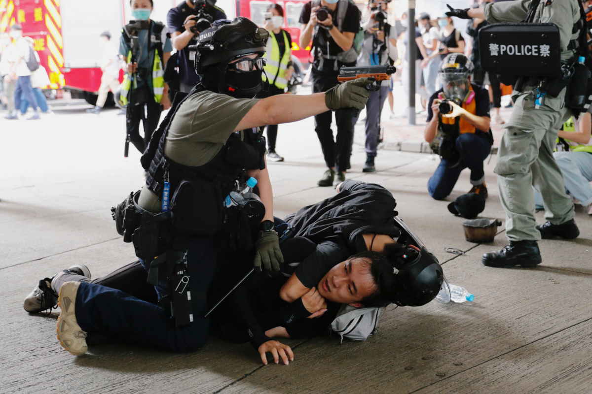 A police officer raises his pepper spray handgun as he detains a man during a march against the national security law at the anniversary of Hong Kong